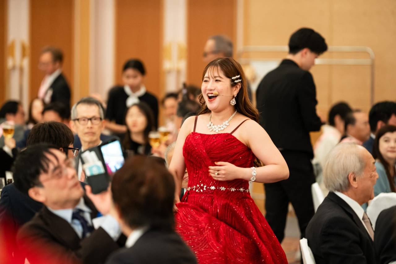 ソプラノ歌手が後方扉から登場しオペラ椿姫の乾杯の歌を披露している様子